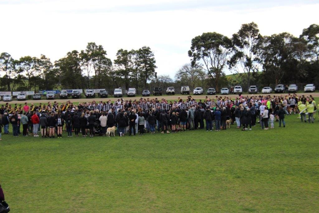 The Poowong Football Netball Club, with the support of their opponents Lang Lang, come together for 