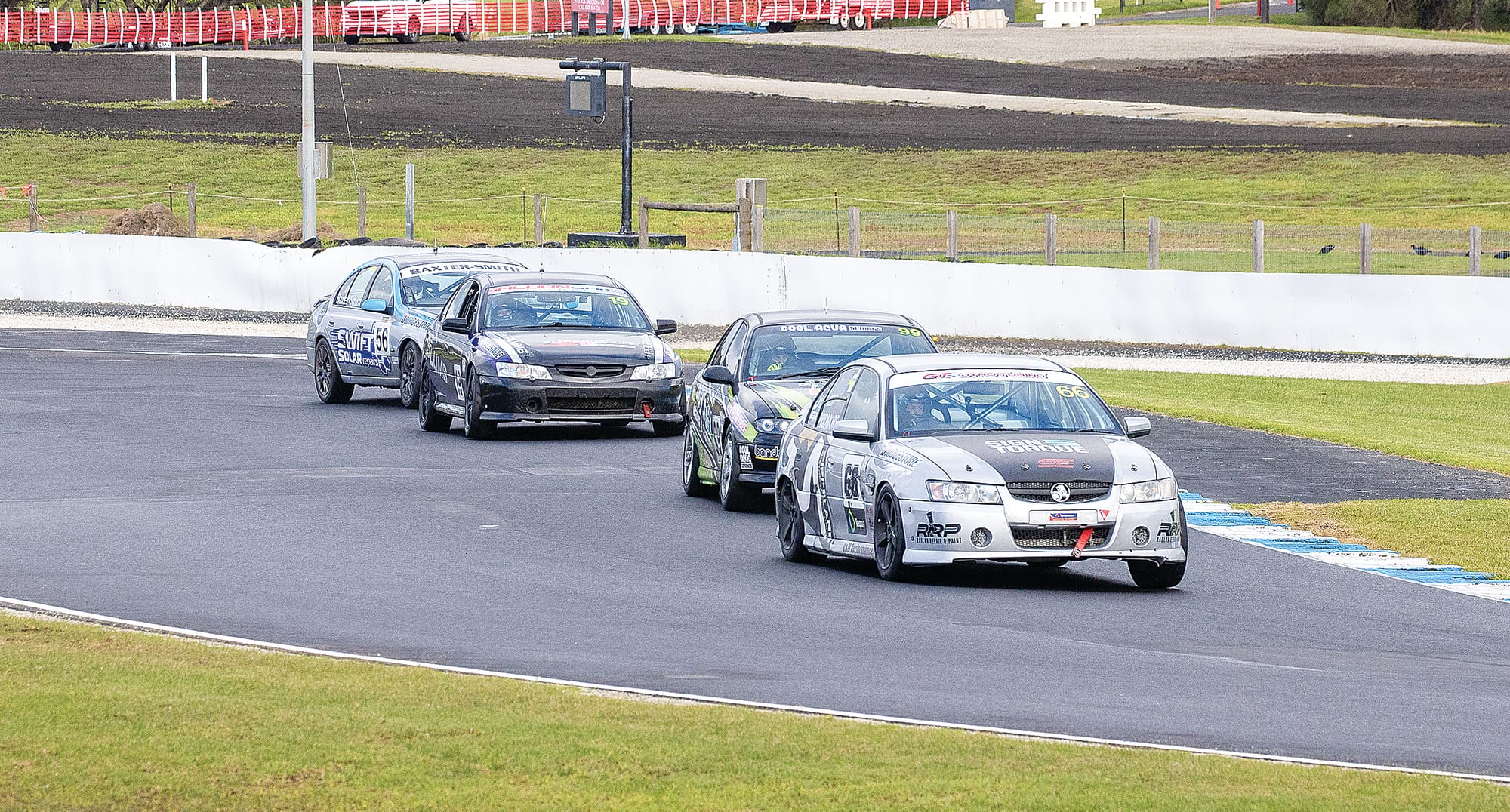 In a nip and tuck stoush Kerran Pridmore got the job done despite some close attention in the Saloon Car race. Photo: Peter Cleeland.