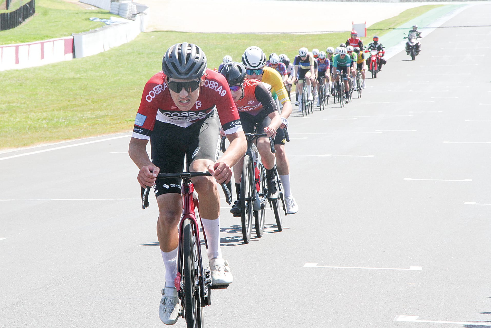 U19 men’s peloton trailing behind the race leaders in the Tour of Gippsland at Phillip Island. B15_4124