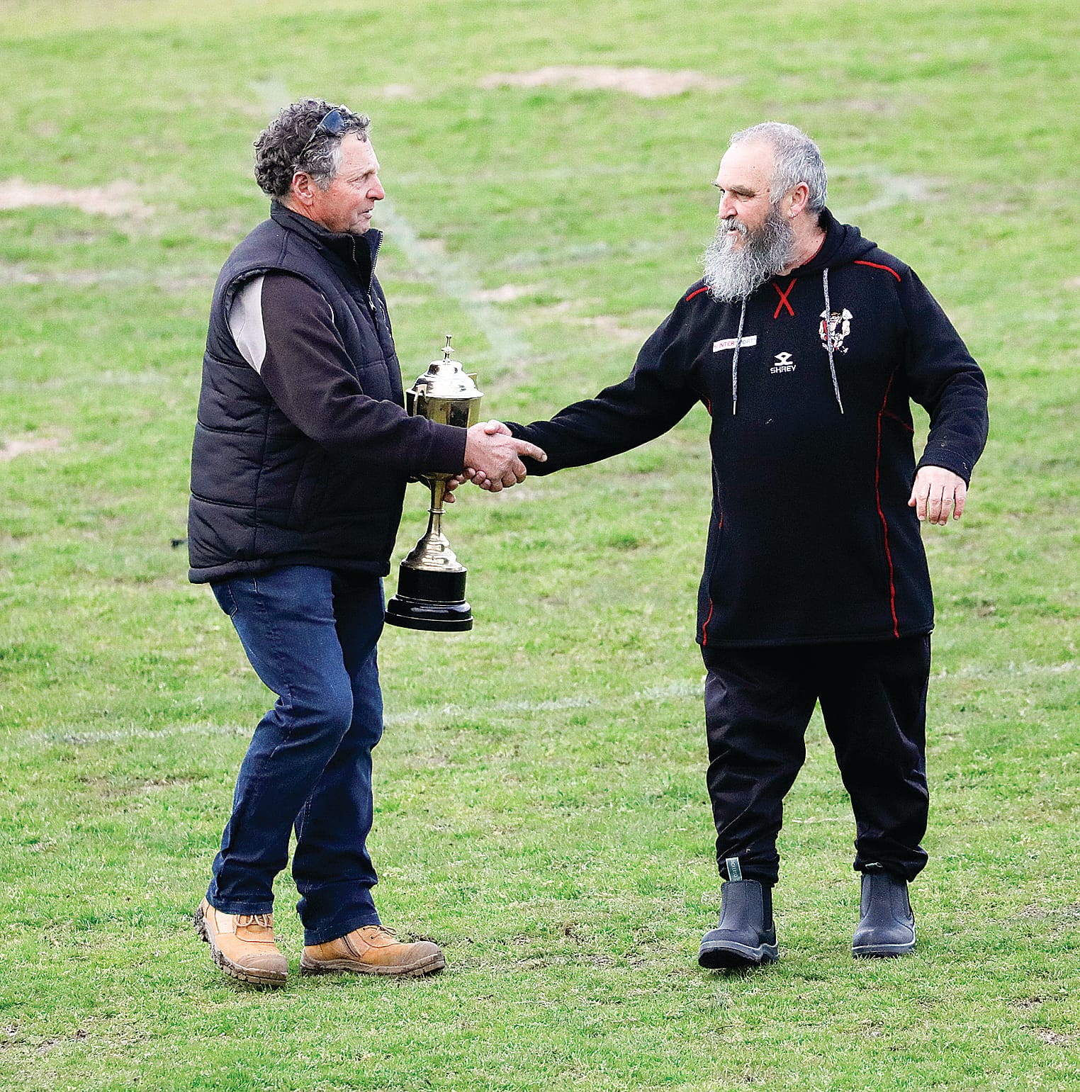Nyora’s president David Chippett congratulating Poowong president Ted Attenborough on retaining the Demon Cup.