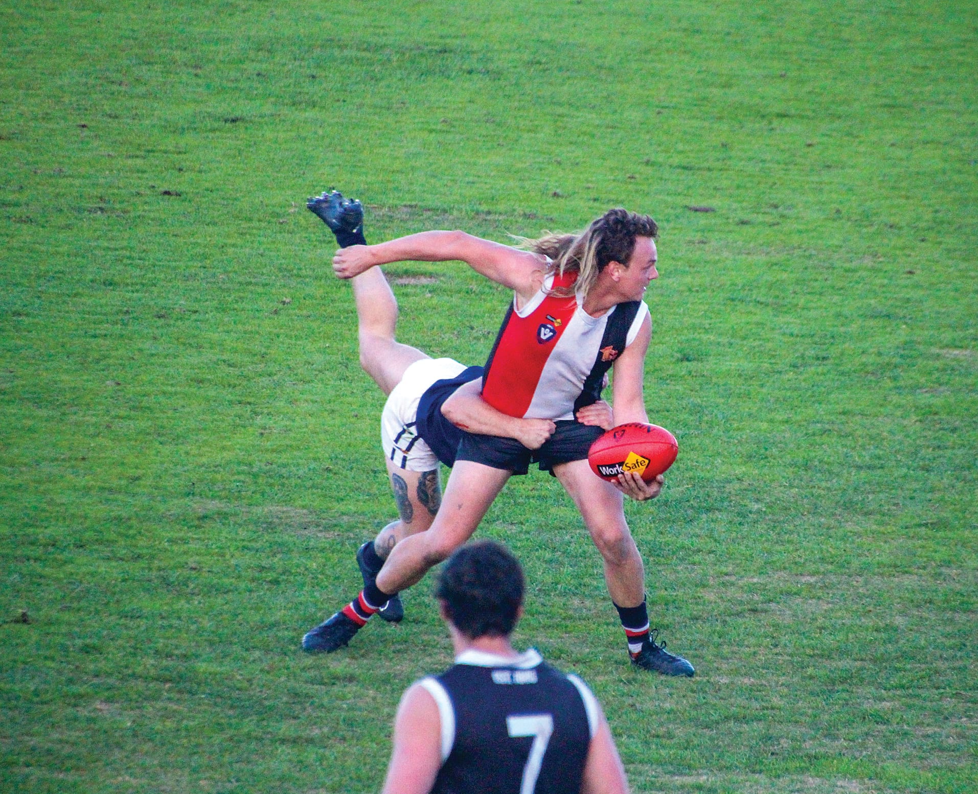 Lucas Lee manages to complete this hand ball regardless of the tackle.