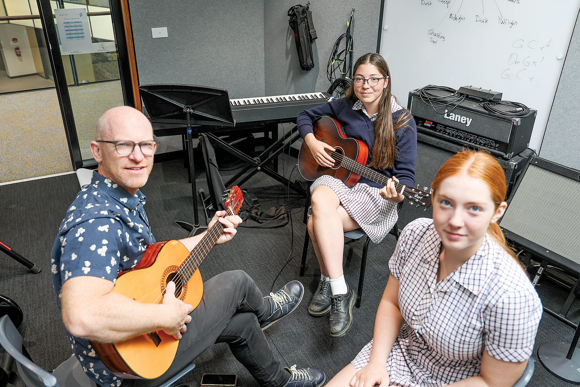 Guitar teacher at Newhaven College David Prideaux works through a few chords with Eve Oakley and Jamilla Prideaux in the college’ performing arts facility.

