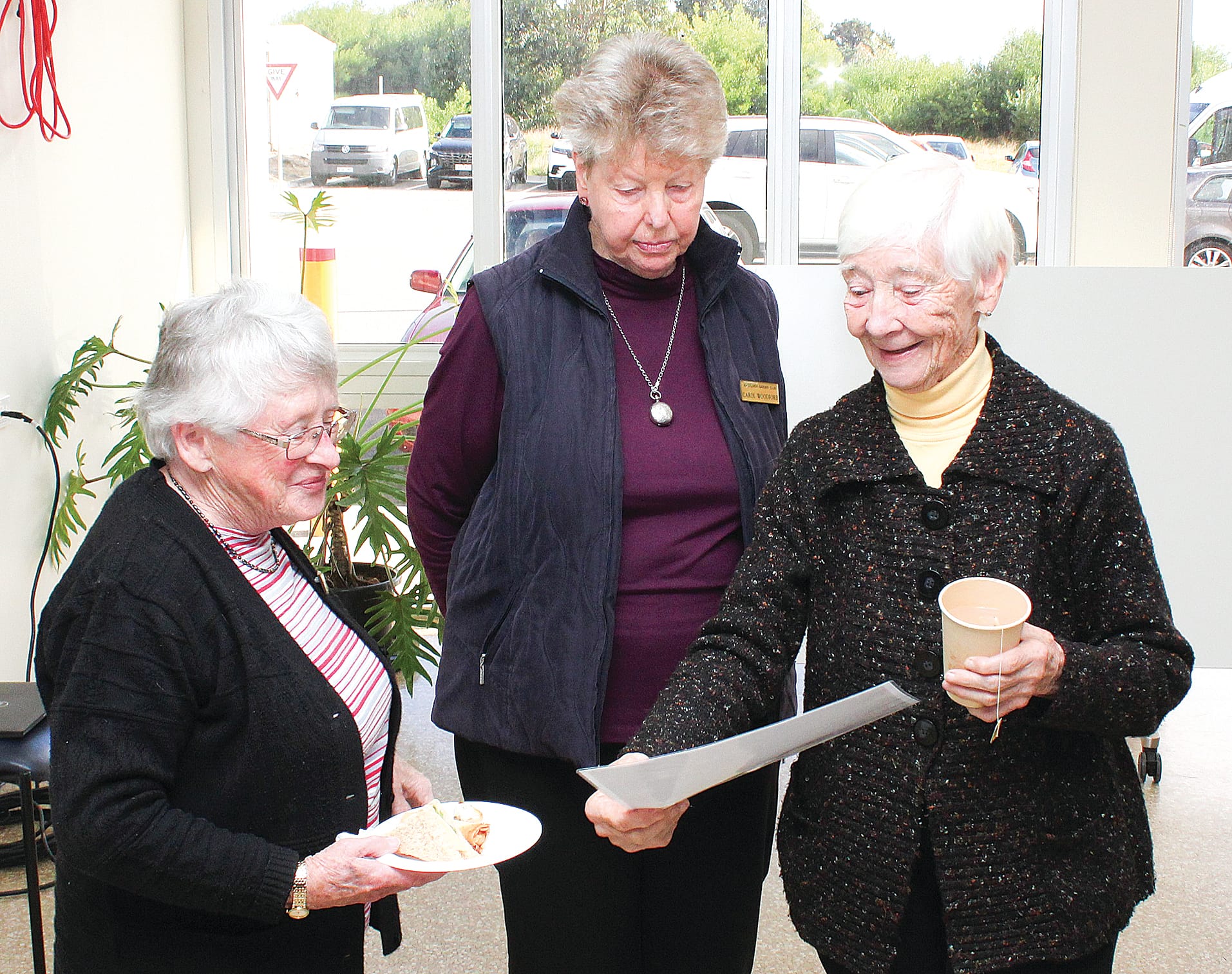 Inverloch Garden Club member Bev Phillips, Carol Woodford and Beryl Millman discuss a certificate of appreciation they received for donating to the Inverloch Fundraising Auxiliary.