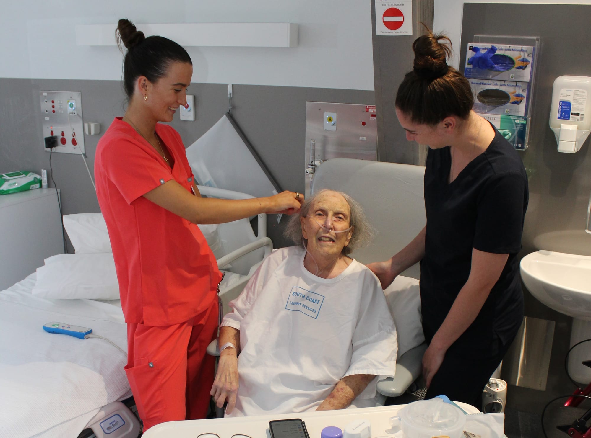 Graduate Nurse Zoe Atkins combs the hair of patient Patricia Labonte in Armitage House, Wonthaggi Hospital, with Endorsed Enrolled Nurse Maggie Gibson. 