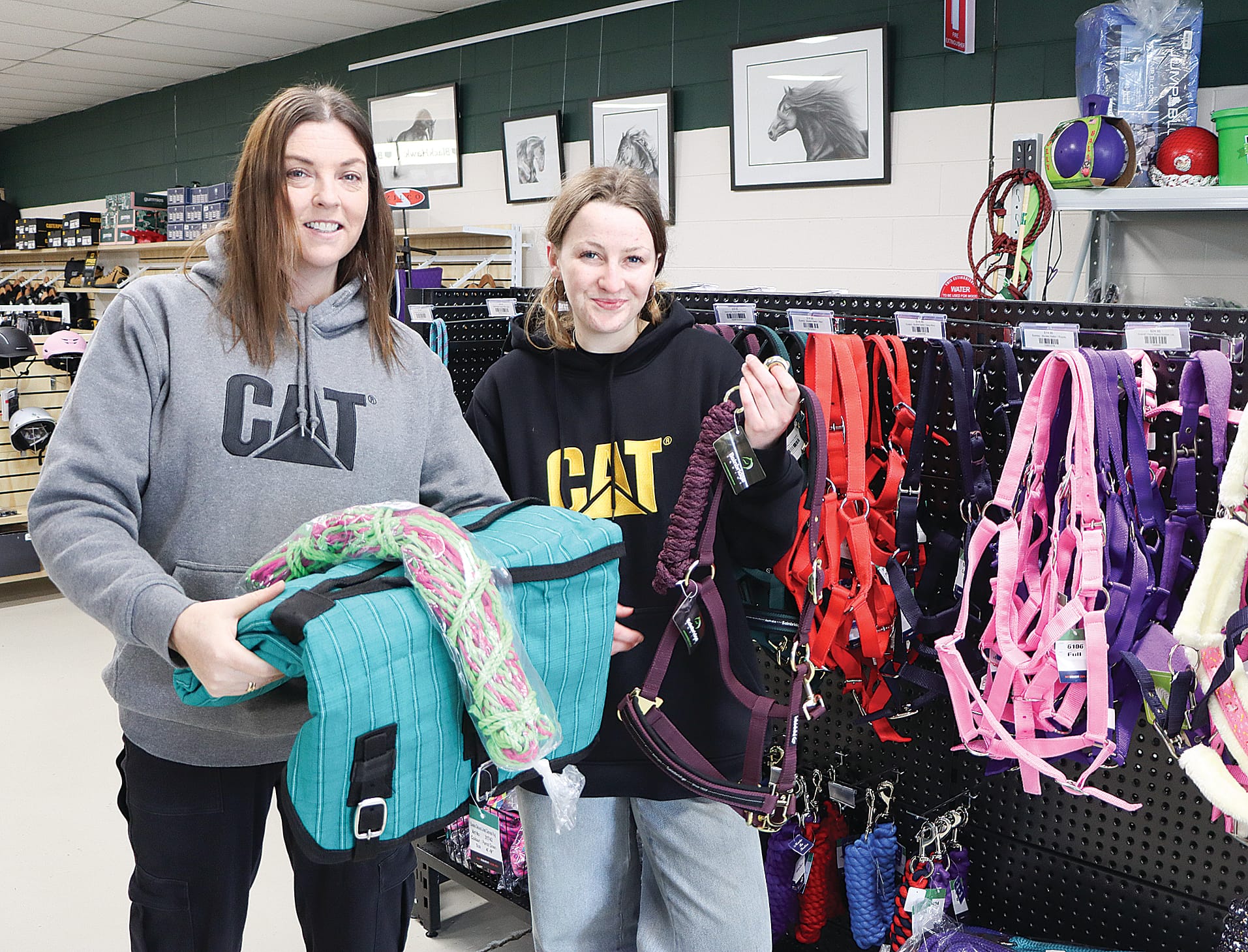 Kristy Barry and Elispeth McInnes show off items including a halter and matching lead rope, a canvas rug and a hay bag. A16_2825
