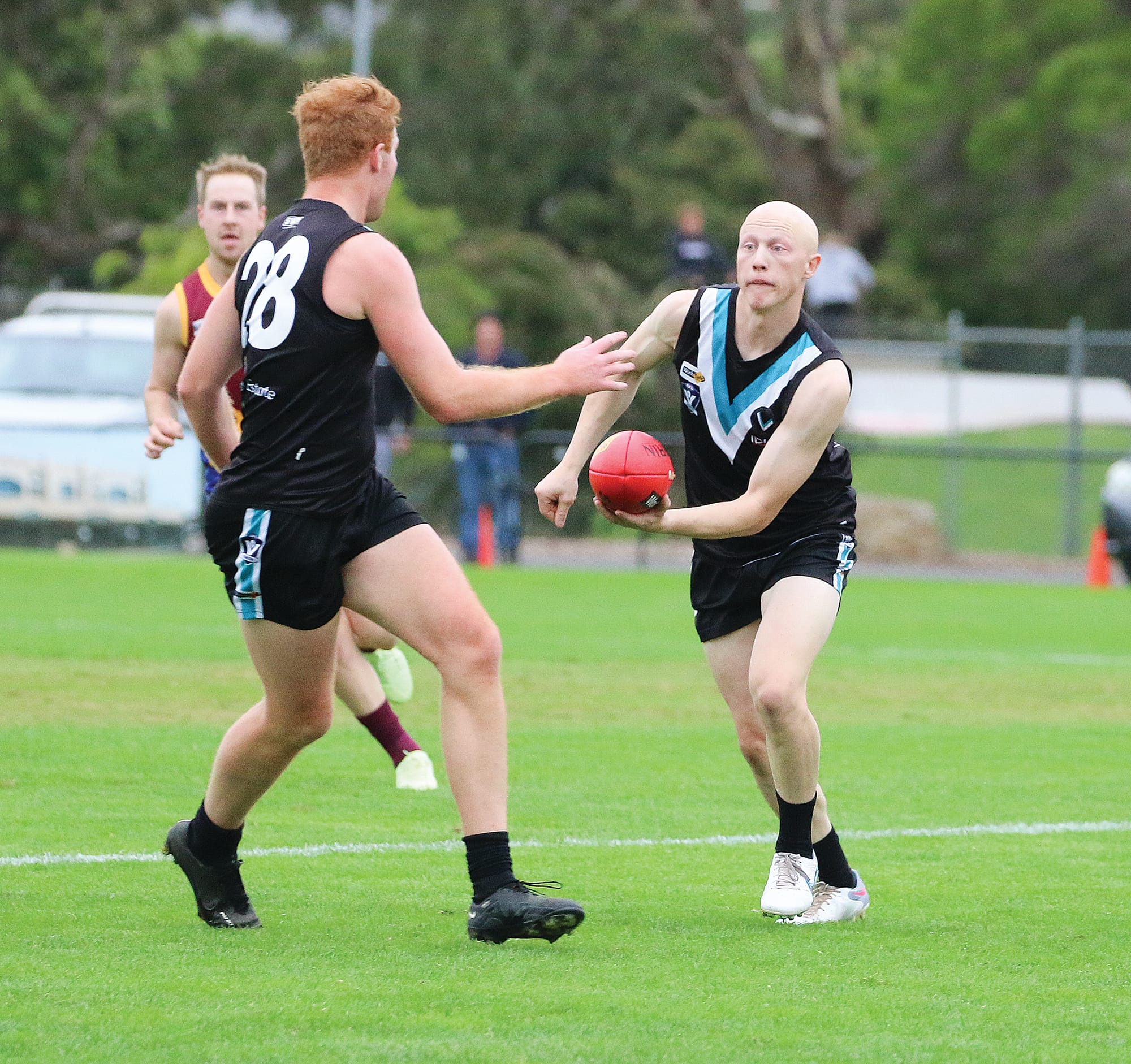 Powers Jye Gilmour handballs it off to teammate in the clear Kyle Reid. 