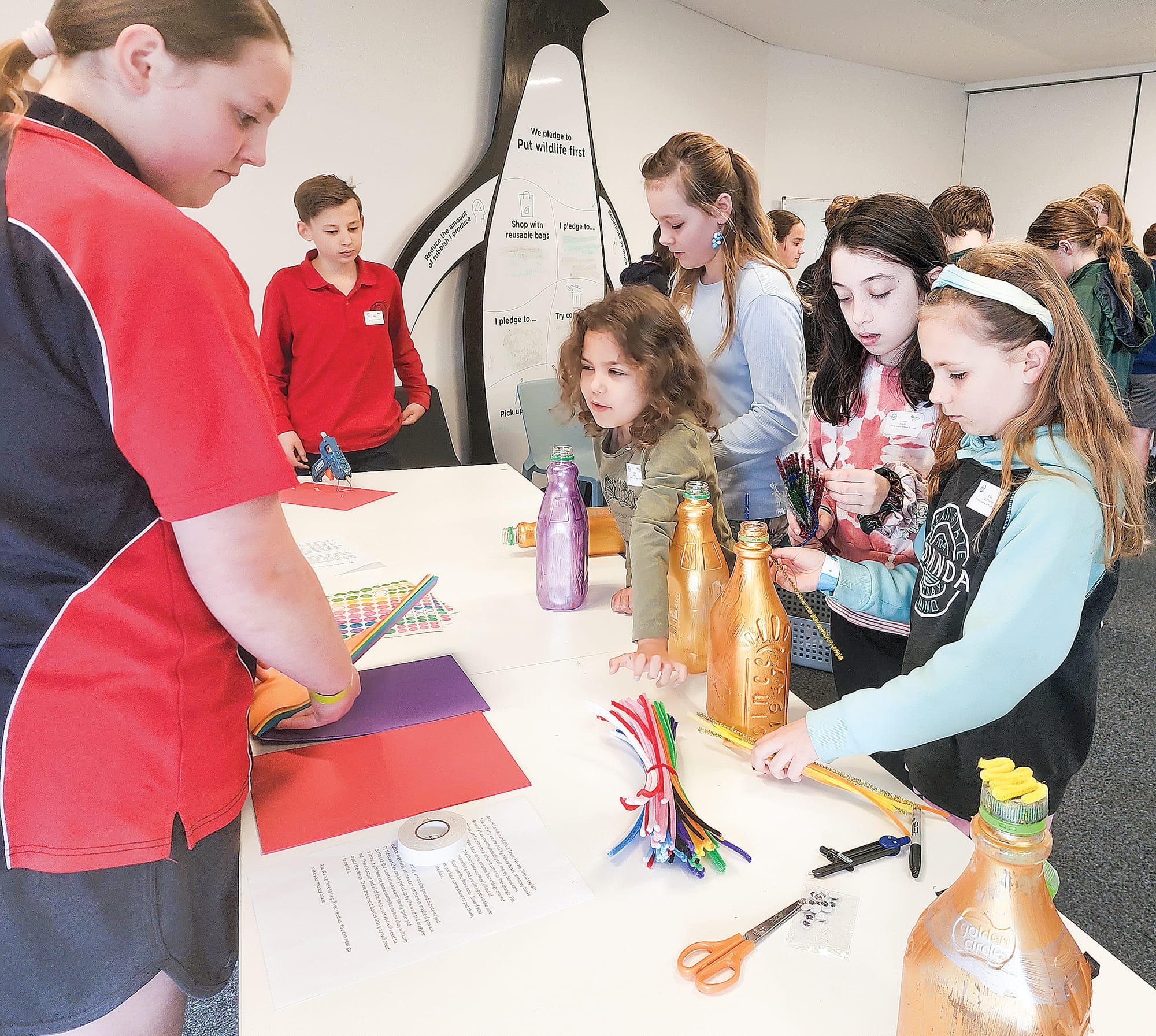 Blue Group delegates gather to learn how to make a money box from upcycled plastic water bottles. 