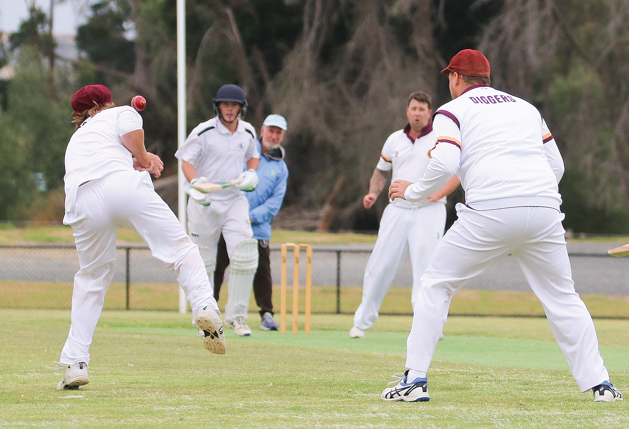 The ball slips through OMK fielders fingers. 