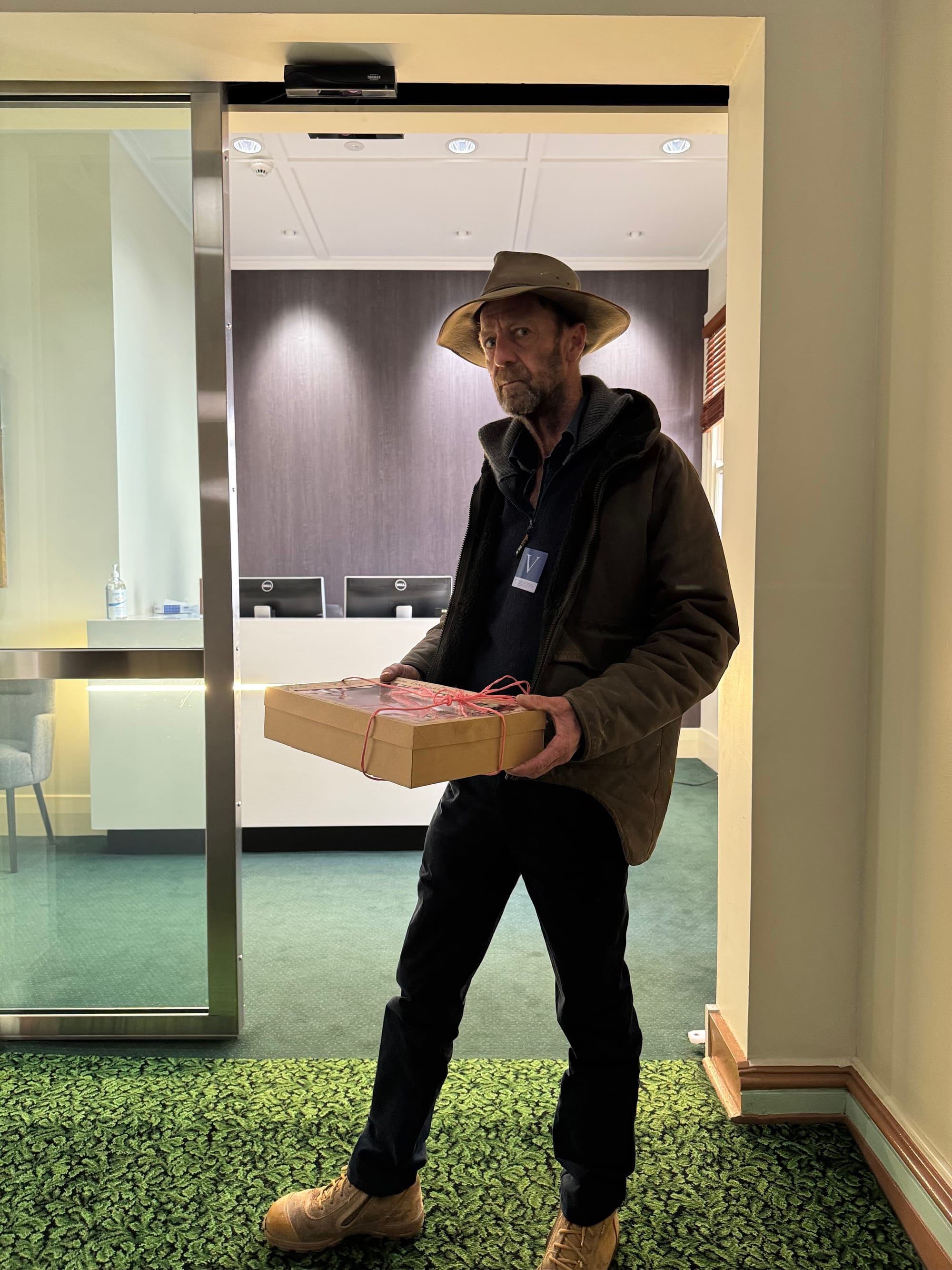 Farmer and CFA volunteer Rob Armstrong delivers a statement from Brutus the Bull about the planned new emergency services levy to the office of Premier Jacinta Allan.

