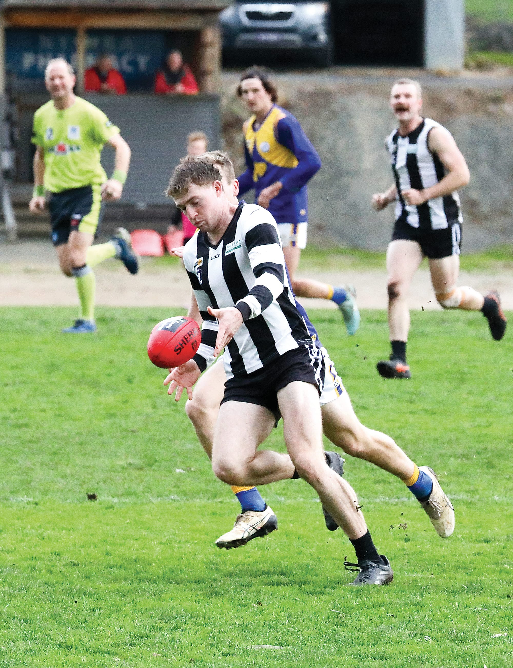 Poowong’s Micah Williams boots the ball under pressure in the seniors match. Photo: Jeff Tulll.