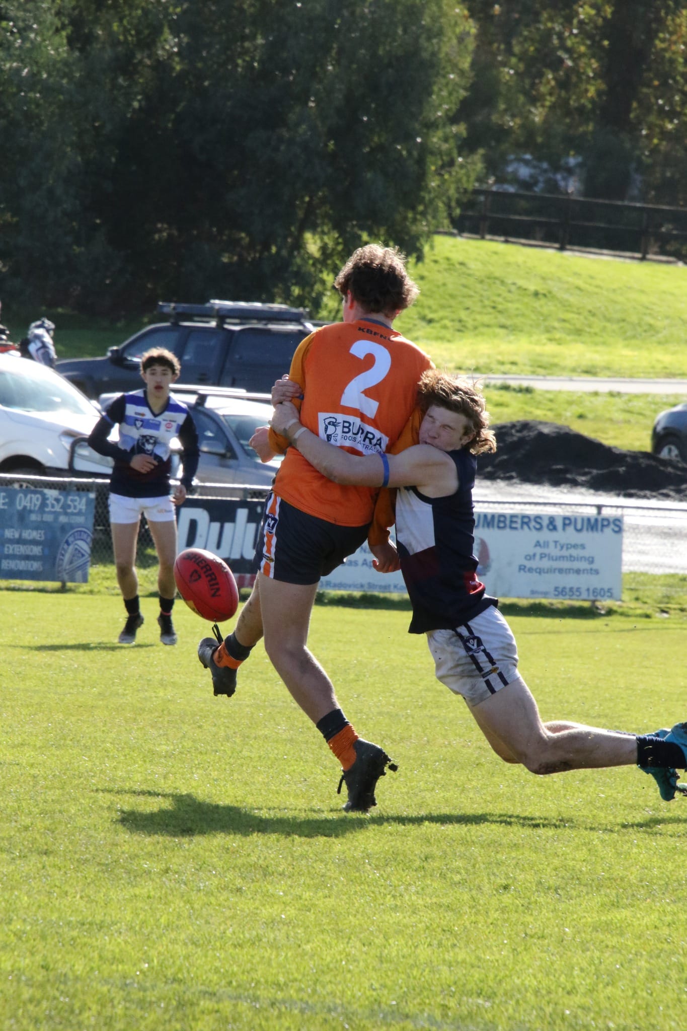 Jake Fowles kicks the ball whilst being tackled. Photo Credit: Phantom Photos. 