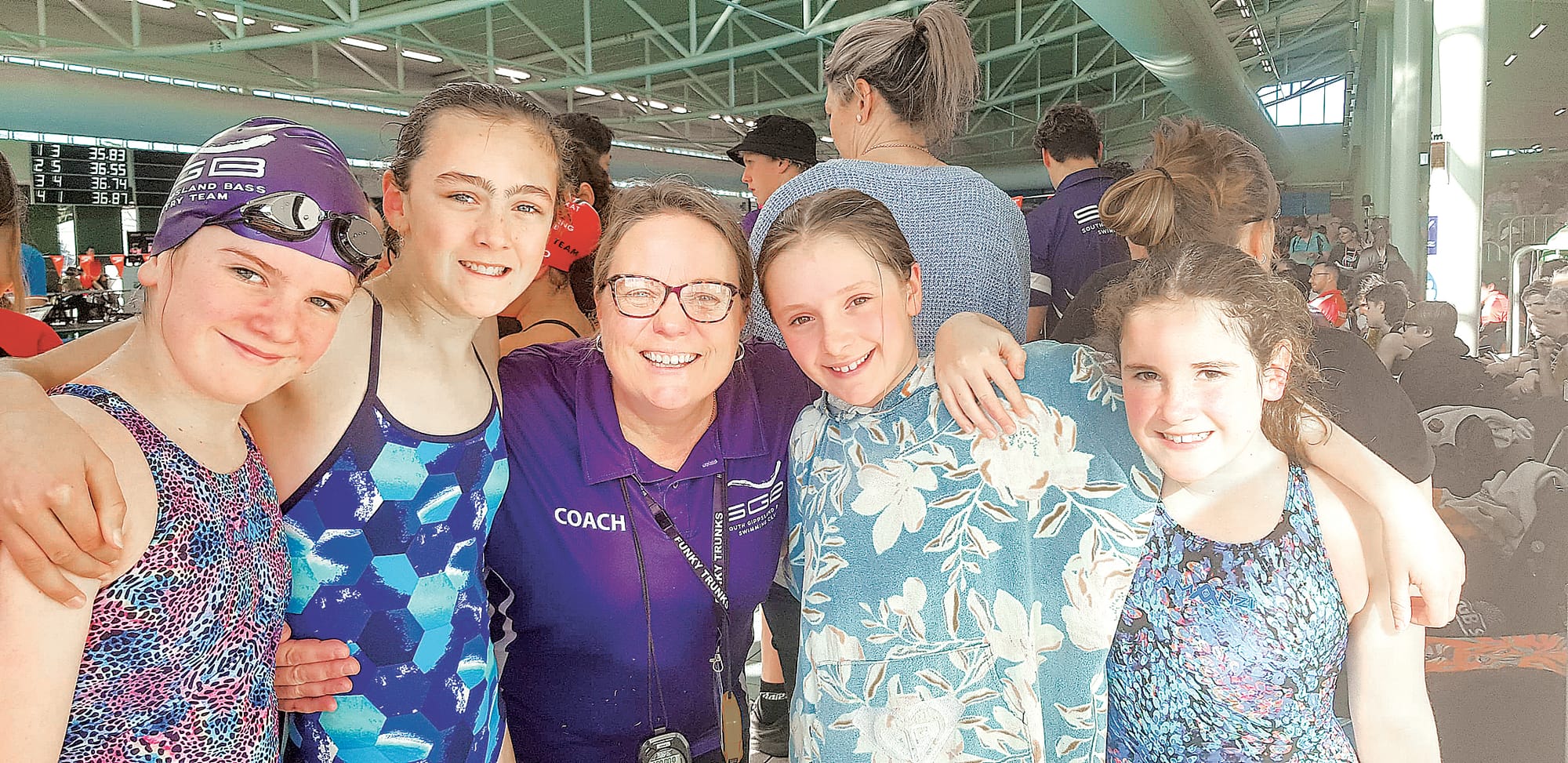 Newly capped swimmers Isobel, Bec, Amalia and Emily celebrate with coach Sam after their first race.