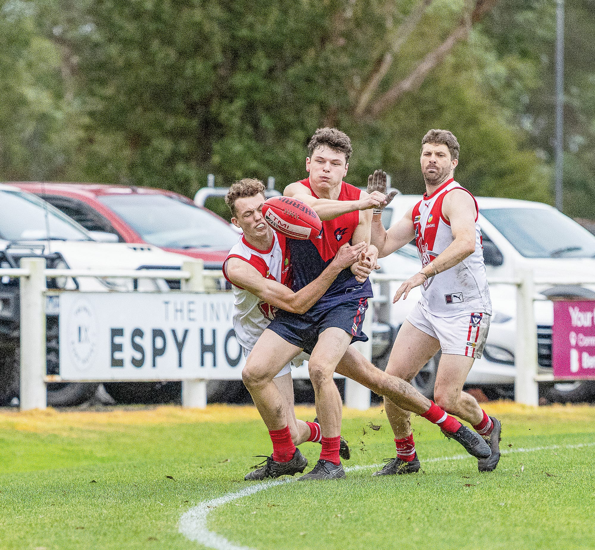 Jarvis Lacy holds his ground under pressure, handballing the Sherrin to a teammate while pinned against the boundary. Photo: Bec Casey Sports Photography.
