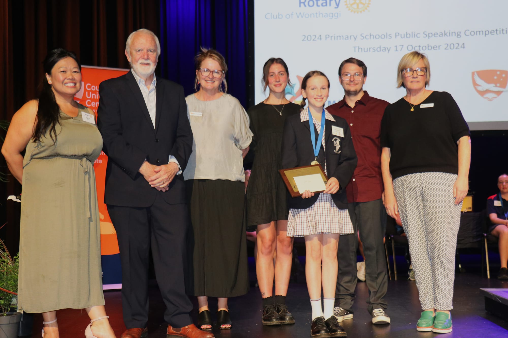 Nicki Chung, Don Paproth, Amanda Mc Mahon, Sophie Hogan, Alex Charlton, and Sarah Bourke presenting the 2024 Primary Schools Public Speaking Competition second place prize to Sophia Hardy of Newhaven College. 