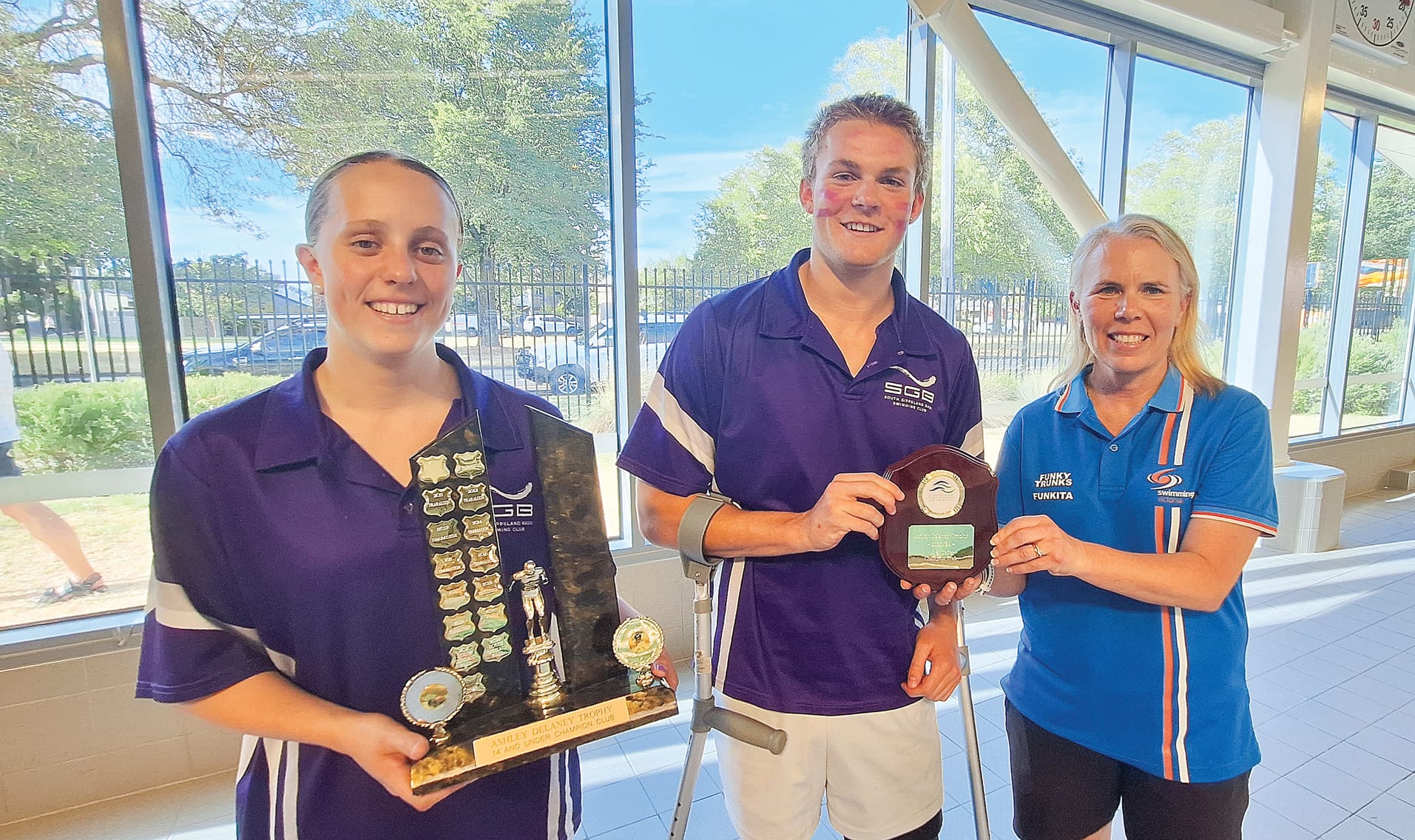 Captains Trinity and Cooper accept the Ashley Delany Trophy from Swimming Victoria president Michelle Harris.
