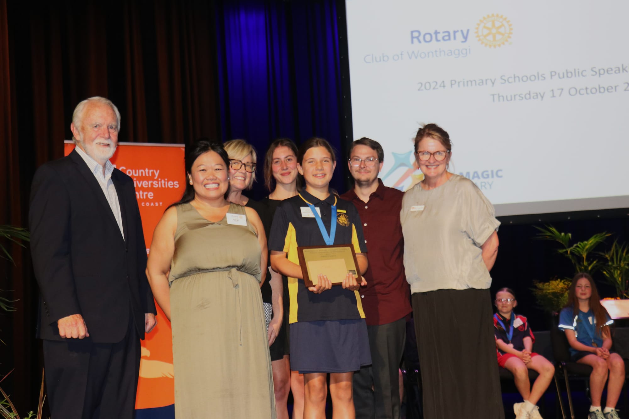 Don Paproth, Nicki Chung, Amanda Mc Mahon, Sophie Hogan, Alex Charlton, and Sarah Bourke congratulating first place winner of the 2024 Primary Schools Public Speaking Competition to Newhaven Primary School student, Tasmin Watson. 
