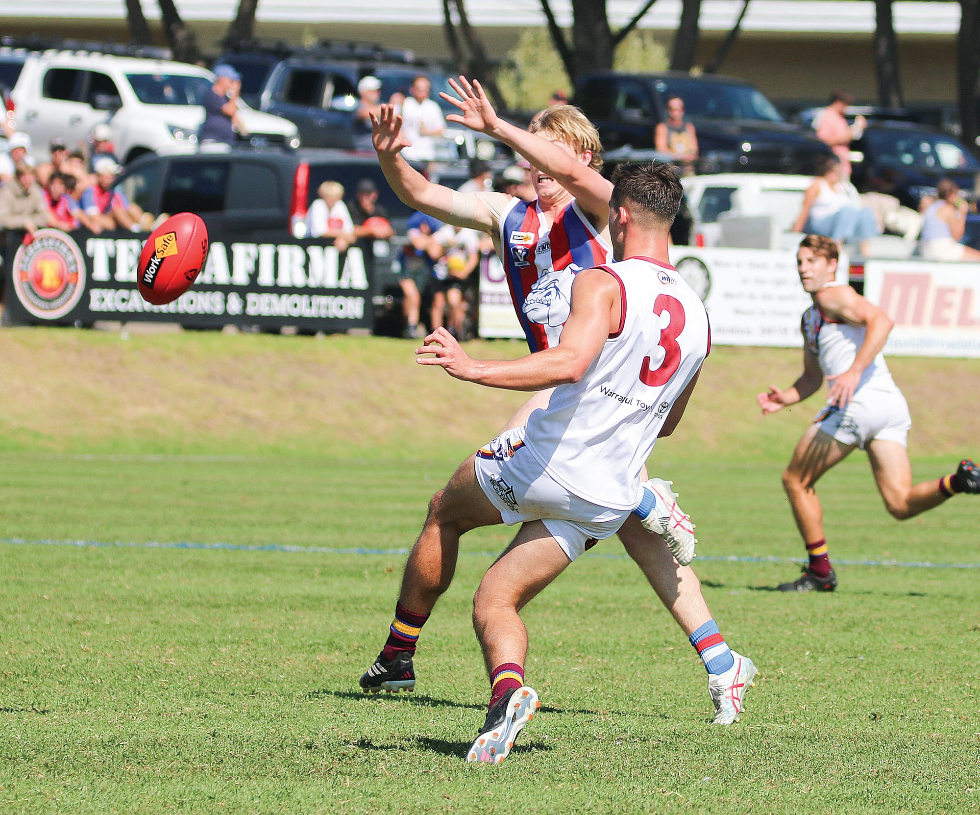Phillip Island’s Charlie Bruce goes to smother a kick from Warragul Industrials’ Travis Ogden.
