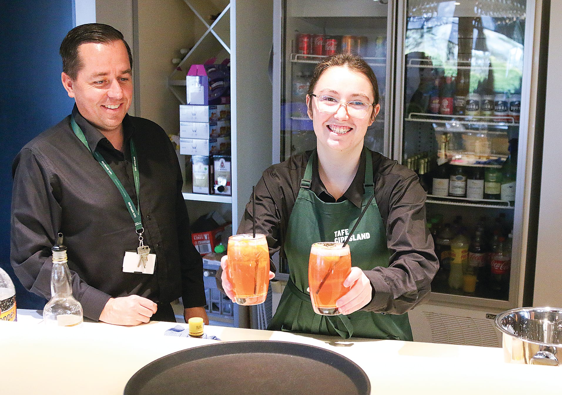 Hospitality trainer Kevin Campbell watches as Ysabella Graham serves her lemon lime and bitters. A03_3022