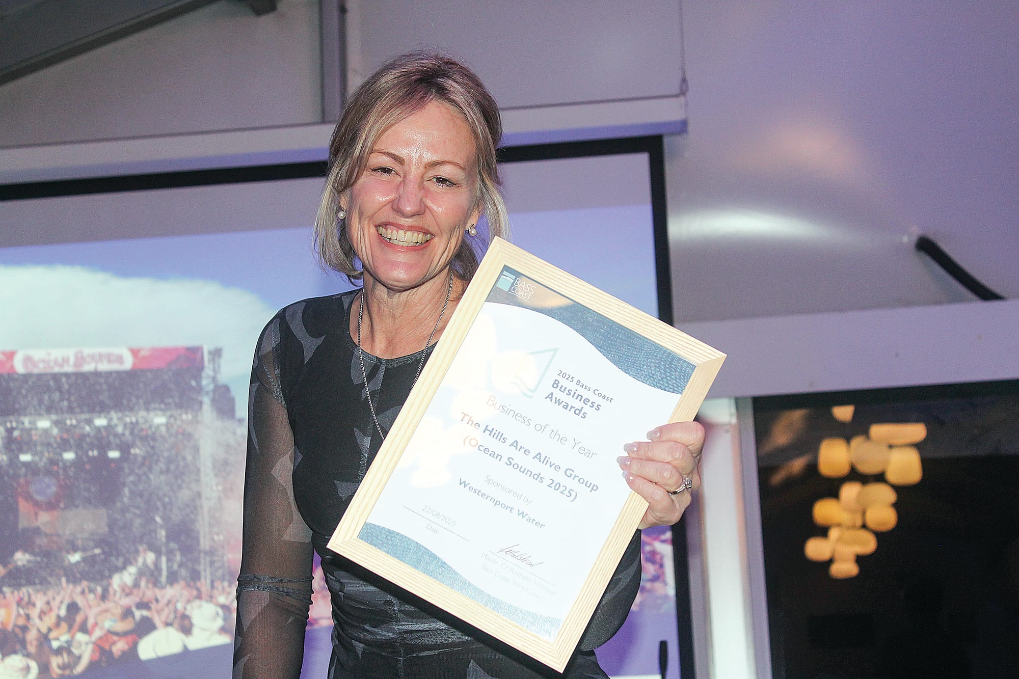 Bass Coast Mayor Cr Rochelle Halstead accepting the Business of the Year award on behalf of The Hills Are Alive Group for Ocean Sounds 2025. B36_3425