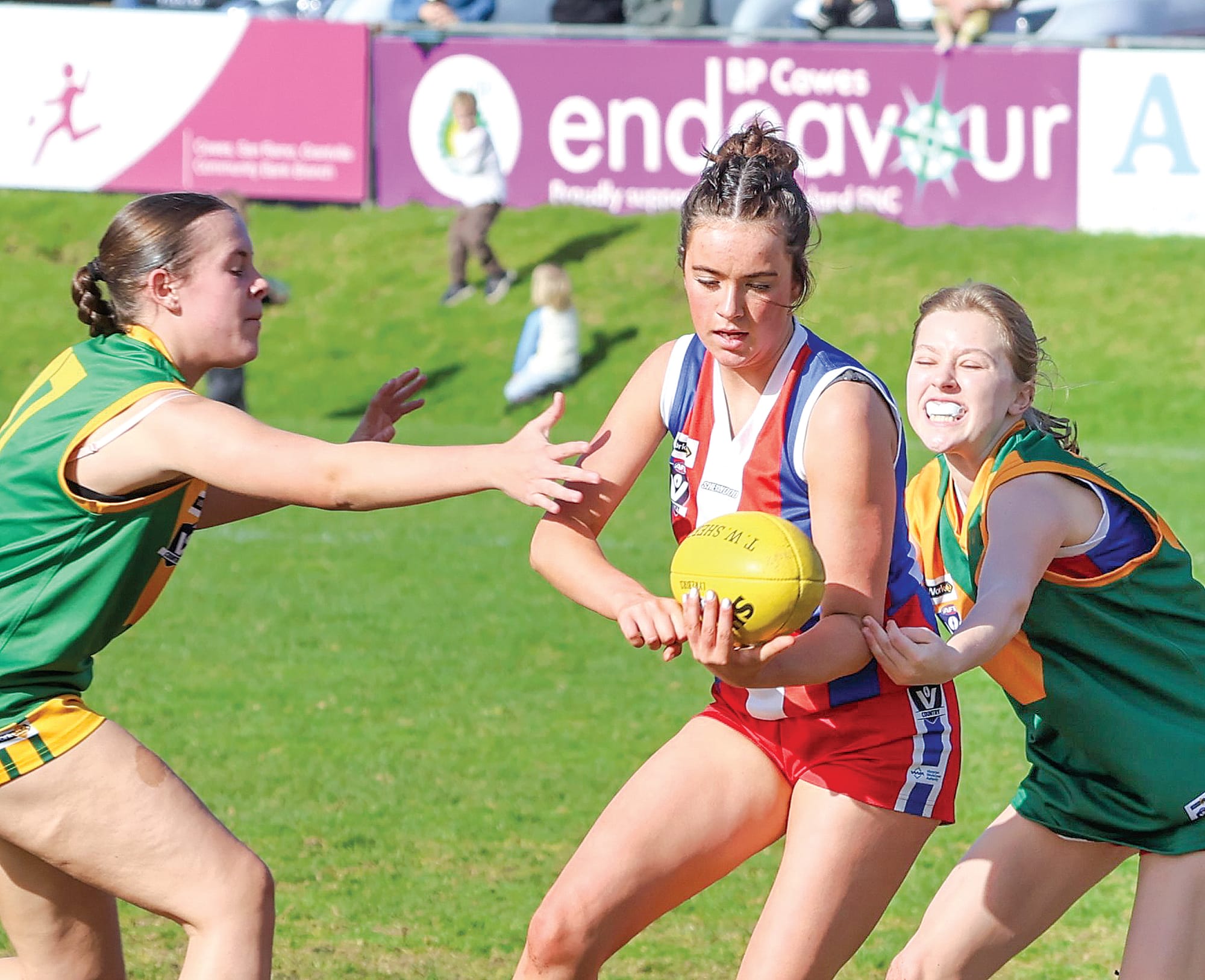 Phillip Island Under 16 Girls player Jazzy Campbell gets her handpass away under pressure from her Hill End opponents.