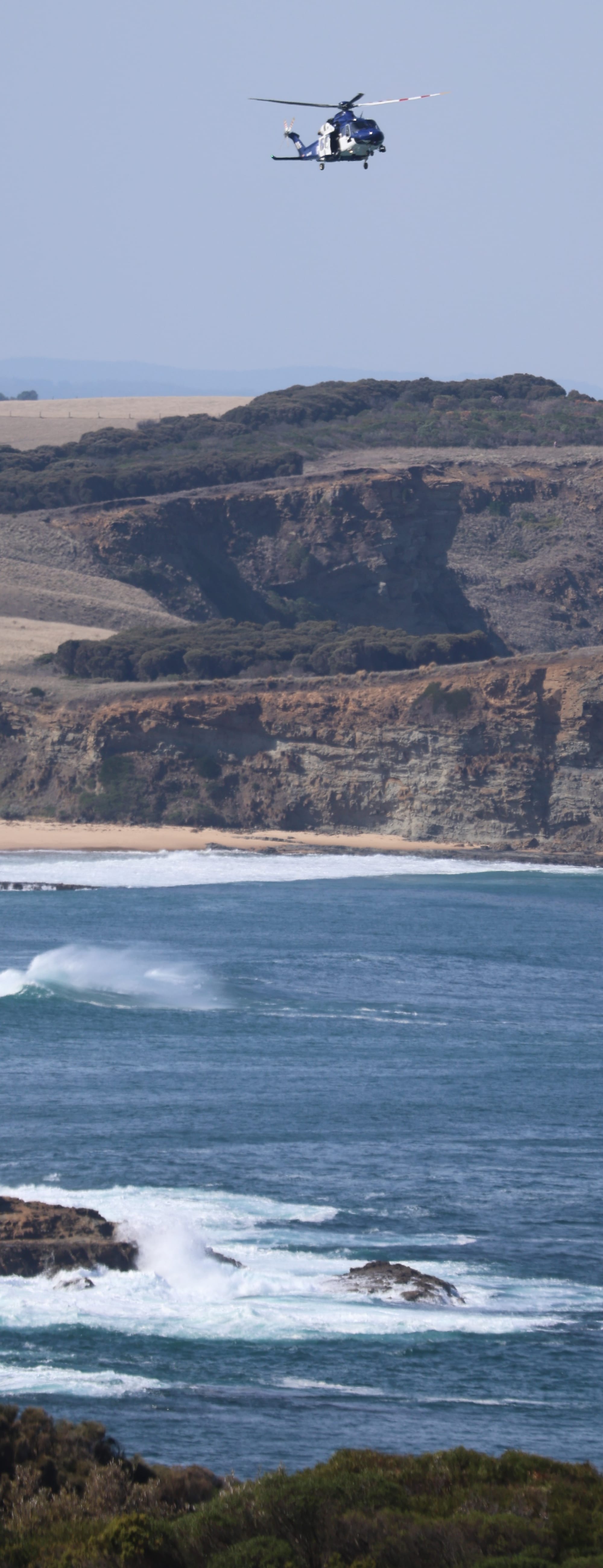 The police airwing searches the rocks and water off Punch Bowl near San Remo on Friday, April 18.
