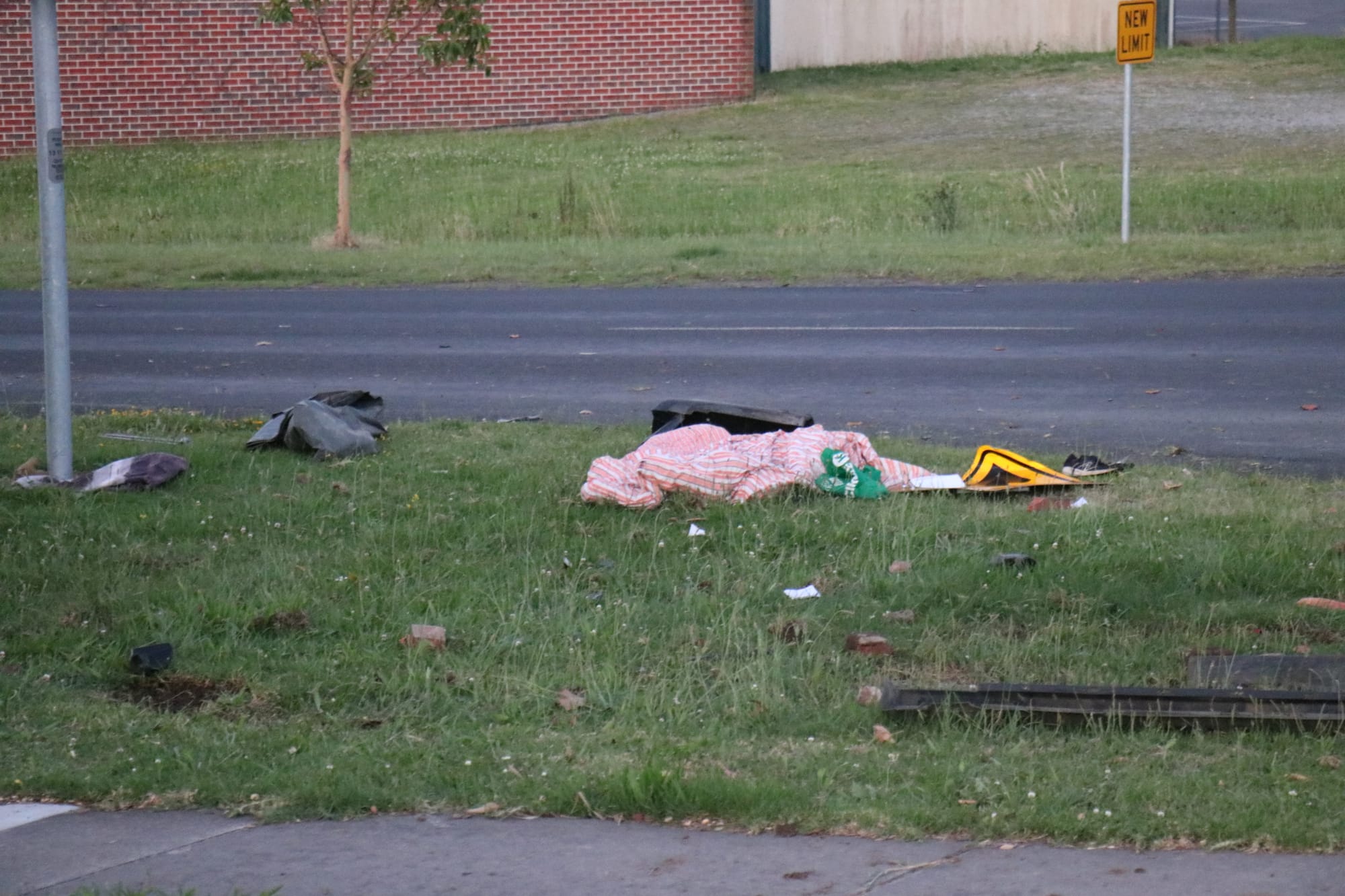 A road sign lies amongst debris after a black ute collided with a gum tree.