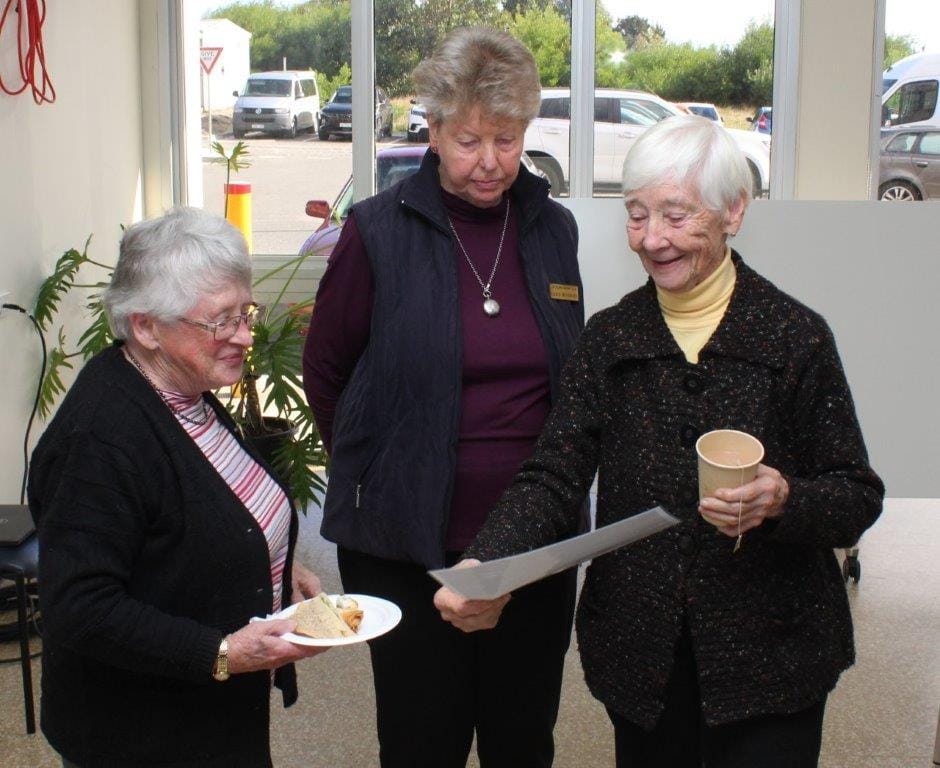 Inverloch Garden Club member Bev Phillips, Carol Woodford and Beryl Millman discuss a certificate of appreciation they received for donating to the Inverloch Fundraising Auxiliary.