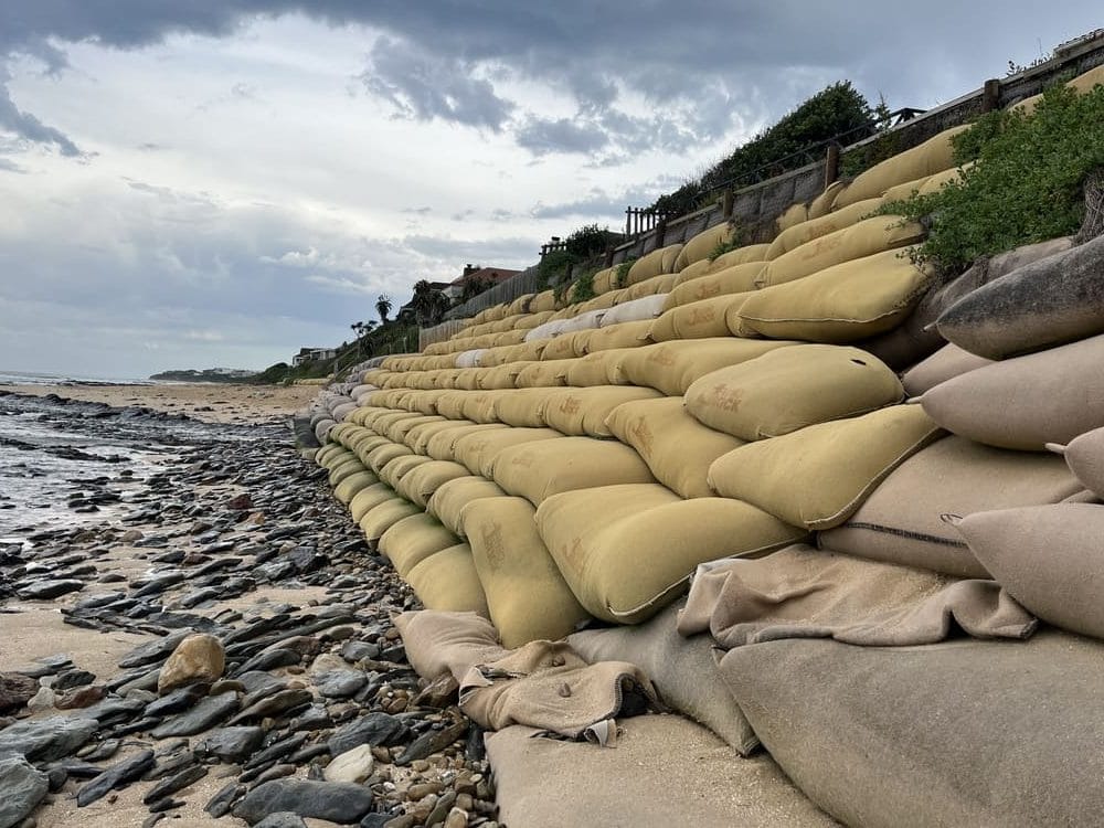 Some say the use of geotextile bag walls and other vertical revetment will lead to more sand being stripped off the Inverloch Surf Beach, but what's the alternative if you want to protect housing and infrastructure?