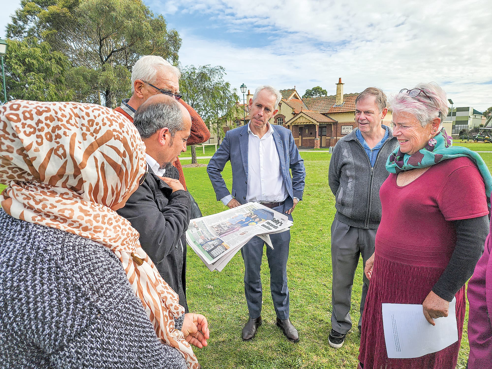 Minister Giles watches closely as Lukman and Khadija react to a story on their journey to date in the Herald Sun.
