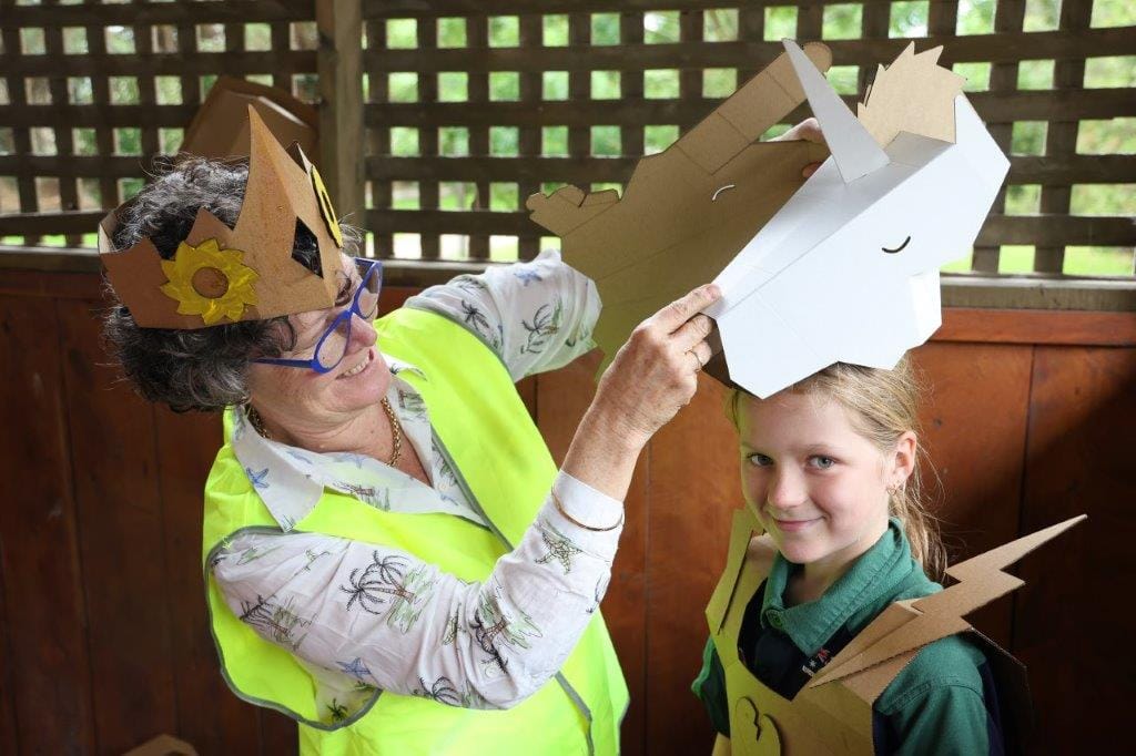 Fishy Stories Festival volunteer Deb Benkemoun fits a ‘Box Wars’ helmet on Mieka.
