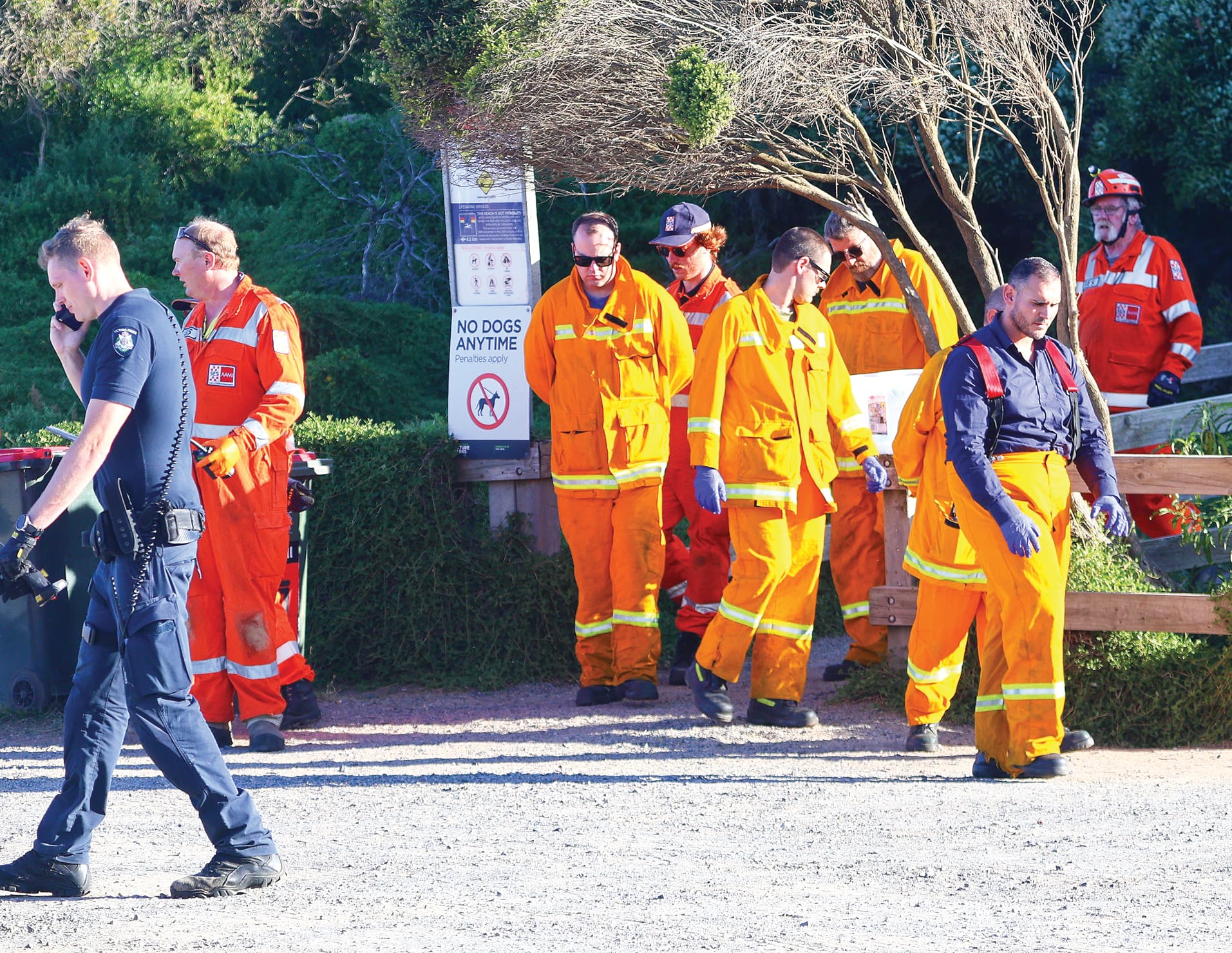 Emergency service personnel leave the beach at Forrest Caves last Wednesday evening, passing the small warning sign at the bottom of the walkway, after recovering the bodies of three of the four victims. A fourth victim was airlifted but later died in hospital.